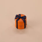 Orange round gift box with a blue ribbon on a beige background