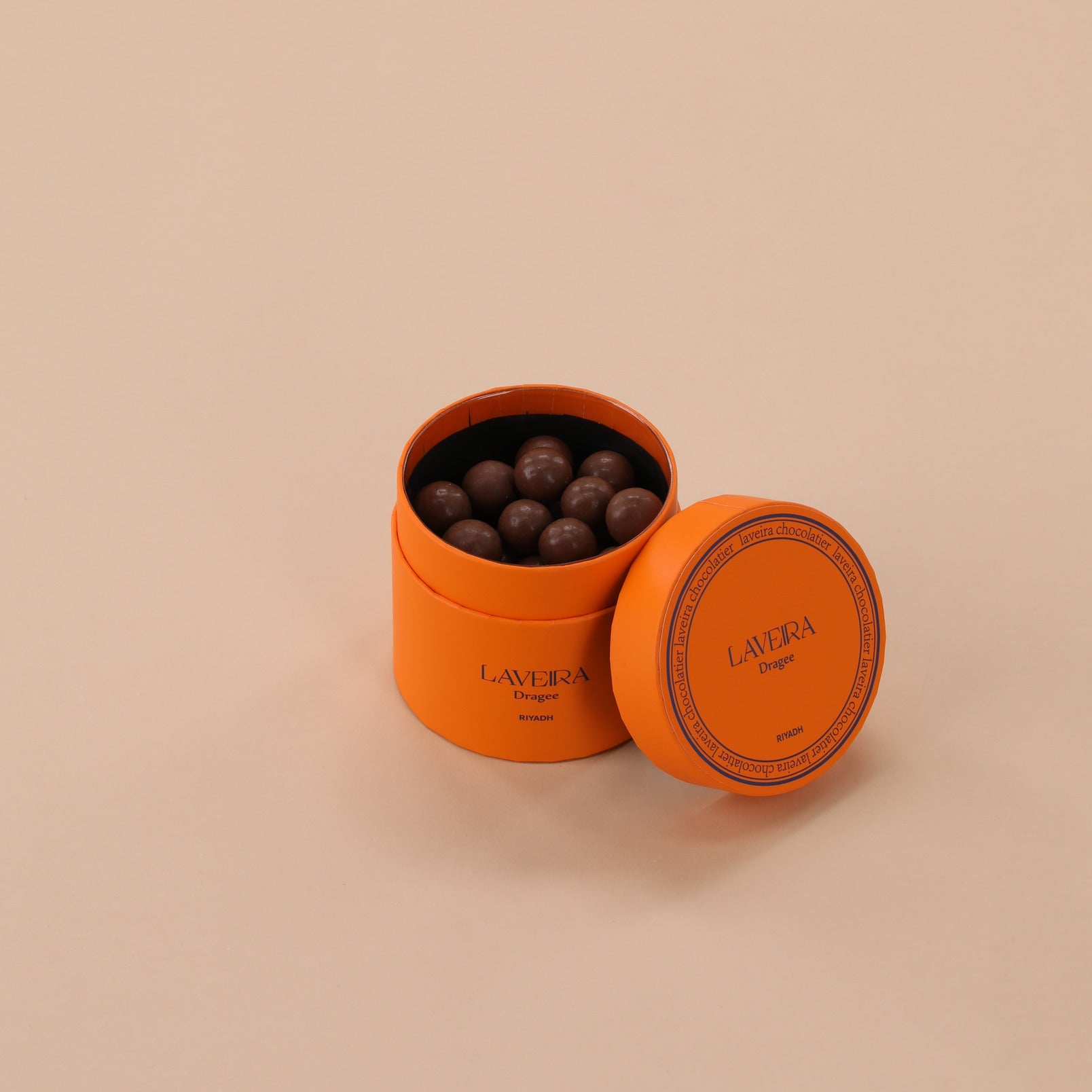 Orange tin with chocolate truffles on a beige background