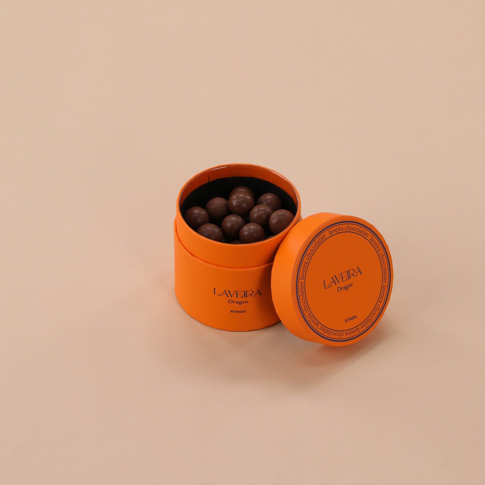 Orange tin with chocolate truffles on a beige background