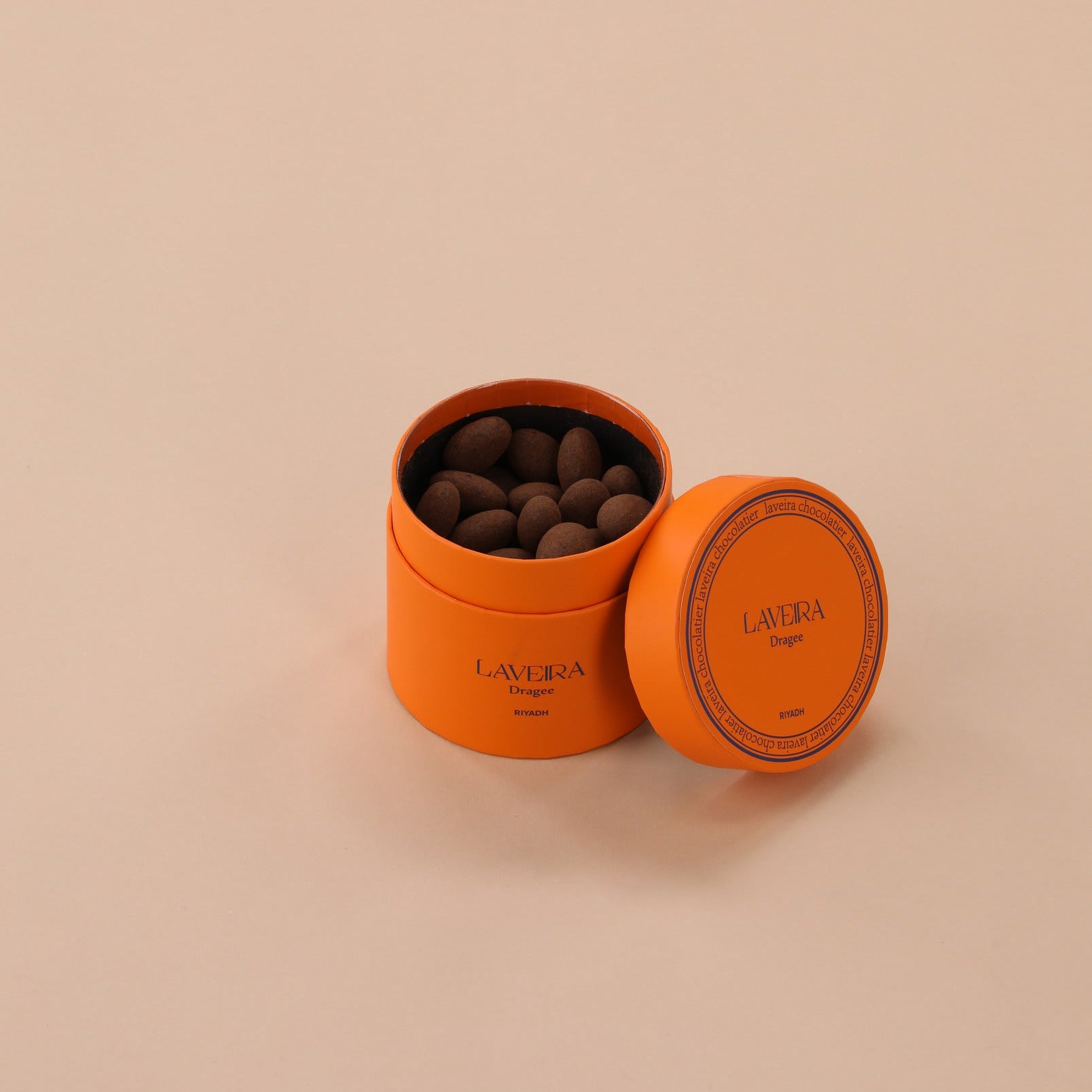 Orange container with chocolate truffles on a beige background