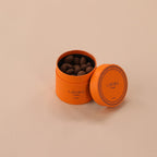 Orange container with chocolate truffles on a beige background